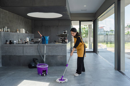 Female Employee Cleaning Modern Coffee Shop Interior with Mop and Bucket in Bright Daylight