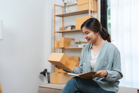 Young Woman Running a Small Online Sales Business from Home, Managing Order and Packaging Productsの写真素材