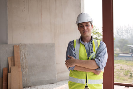 Young Engineer on Construction Site Wearing Safety Gear and Reflective Vest, Confidently Overseeing...