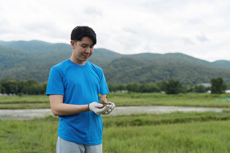 Young Volunteer Planting Trees in a Natural Area to Promote Environmental Conservation and Sustainabilityの写真素材