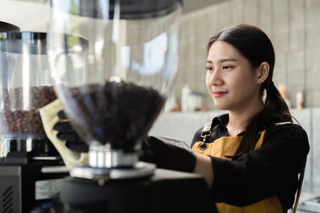 Female Employee Cleaning Coffee Shop Equipment in Modern Cafe Setting with Smiling Expressionの写真素材