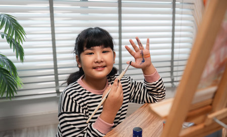 Young Girl Enjoying Her Free Time Drawing and Painting at Home, Expressing Creativity and Artistic Skillsの写真素材