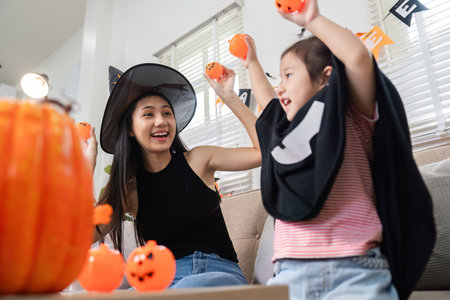 Adorable Mother and Daughter Dress Up and Decorate Living Room for Halloween Celebration with Pumpkins and Festive Decorationsの写真素材