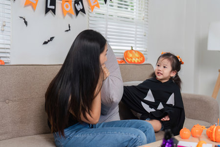 Mother and Daughter Enjoy Halloween Activities Together at Home with Decorations and Costumesの写真素材