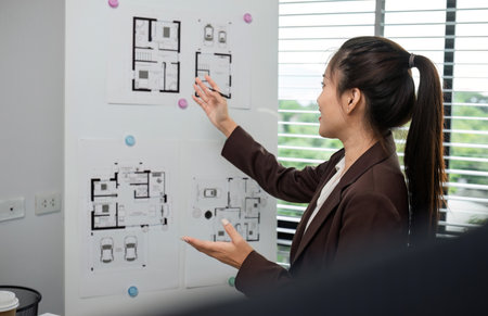 Businesswoman Planning and Presenting a Project with Diagrams on a Whiteboard in a Modern Office...