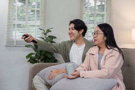 Mother and Son Relaxing Together in Modern Living Room, Watching TV and Enjoying Quality Time on...