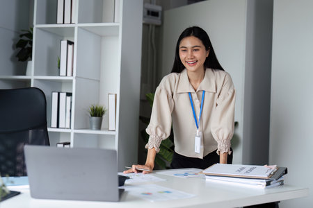 Businesswoman Working on Laptop in Modern Office, Smiling and Engaged in Professional Work...