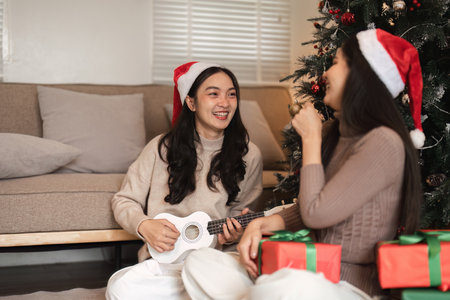 Joyful Young Couple Celebrating Christmas with Gifts and Music by the Tree in a Cozy Living Room Settingの写真素材