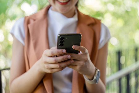 Young woman engaged with smartphone outdoor park lifestyle image natural environment close-up view modern communication conceptの写真素材