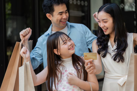 Happy Family Enjoying Black Friday Shopping with Credit Card and Shopping Bags in a Modern Retail Environmentの写真素材