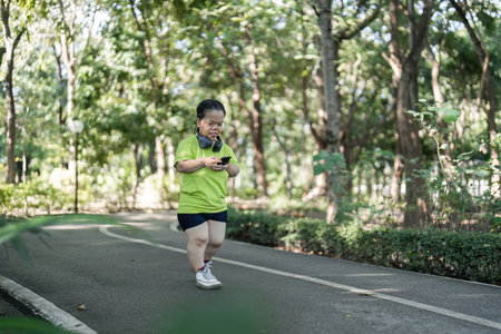 Energetic Petite Woman Jogging in a Lush Green Park on a Sunny Day, Embracing a Healthy Lifestyle and Fitness Routine in Natureの写真素材