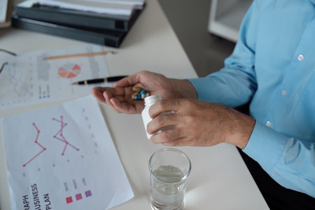 Taking medicine for feeling unwell a business professionals routine office environment health awarenessの写真素材