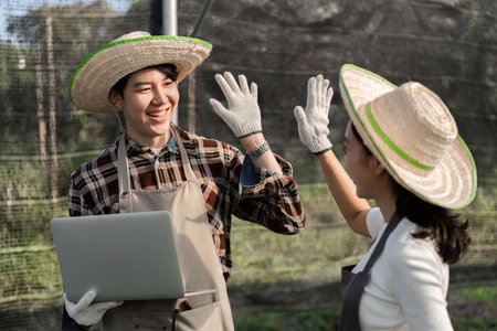 Modern Farmer Couple Cultivating Herbs and Cannabis in a Greenhouse Setting with Sustainable Practicesの写真素材