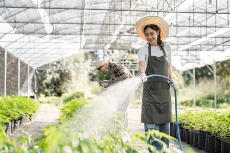 Young Woman Engaged in Sustainable Farming Practices Inside a Modern Greenhouse Environmentの写真素材