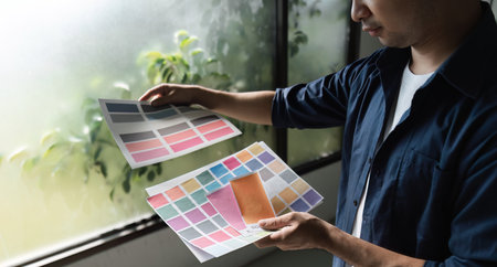 Graphic Designer Selecting Color Palettes for Creative Projects in a Modern Studio Environmentの写真素材