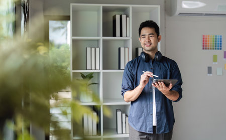Creative Graphic Designer Working on Website Development with Digital Tablet in Modern Office Environmentの写真素材