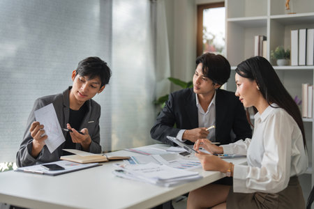 Asian Business Team Meeting for Idea Exchange and Discussion in Modern Office Settingの写真素材