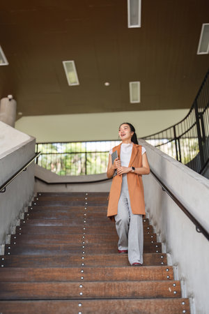 Confident Businesswoman Walking Up Stairs in Modern Office Building with Determination and Style