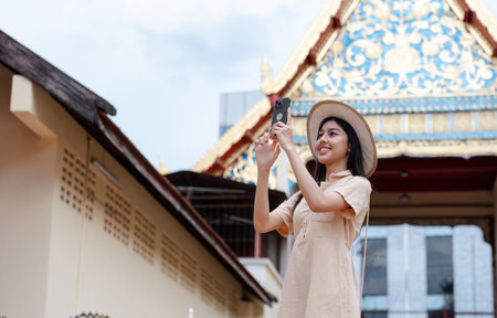 Young Female Tourist Exploring a Cultural Landmark with Mobile Phone in Hand, Capturing Memories and Enjoying the Adventureの写真素材