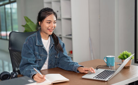 Young Woman Studying Online at Home with Laptop and Notebook, Engaged in E-Learning and Remote...