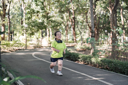 Energetic Woman Jogging on a Serene Garden Path Surrounded by Lush Greenery and Sunlightの写真素材