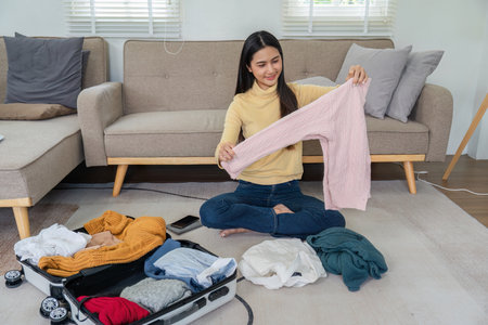 Young Woman Packing a Suitcase in a Modern Living Room, Preparing for Travel or Vacation, Organizing...