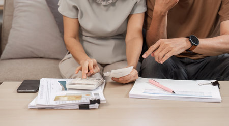 Elderly Couple Collaborating on Family Financial Planning at Home with Documents and Calculatorの写真素材