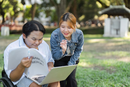Young Disabled Businessman Engages in Productive Outdoor Discussion with Colleagues in a Park Settingの写真素材