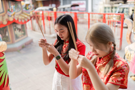 Celebrating chinese new year young women offering incense at temple urban setting cultural ritual close-up viewpointの写真素材