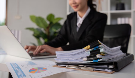 Professional discussing business over the phone in an office with work plan documents on the tableの写真素材