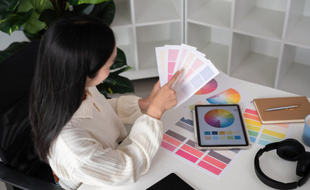 Designer working with color swatches while using tablet for graphic design work at deskの写真素材