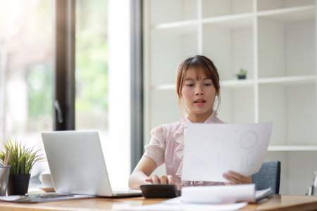 Professional reviewing financial documents and calculations in an office settingの写真素材