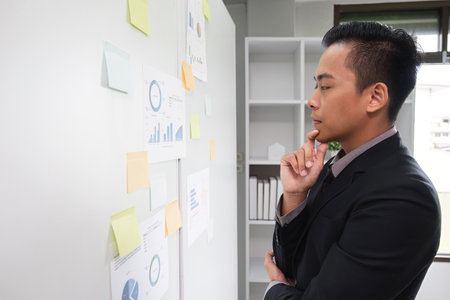 Businessman Analyzing Data on Information Board in Modern Office Setting for Strategic Planning and...
