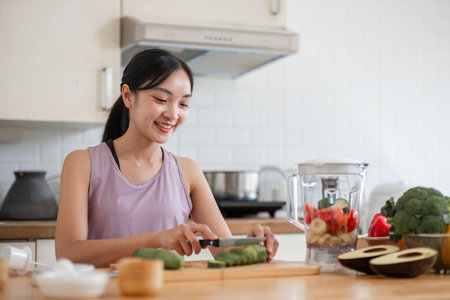 Young Woman Preparing a Healthy Fruit Smoothie in a Modern Kitchen for a Nutritious Lifestyle and Wellness Routineの写真素材