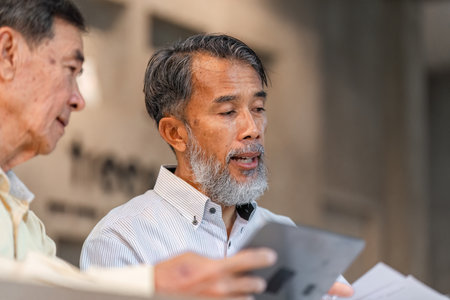 Businessmen discussing project details over coffee in a modern cafe setting with focused dialogueの写真素材