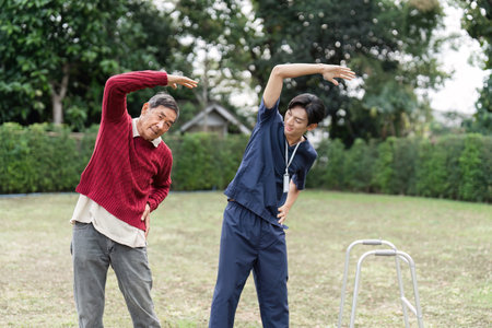 Health caregiver assisting elderly man with stretching exercises outdoors for rehabilitation therapy