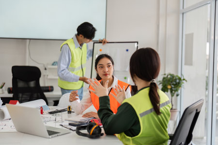 Collaborative construction discussion: architect and engineer strategizing over plans in a modern office settingの写真素材