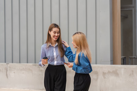 Diverse women walking together and discussing ideas while holding coffee.の写真素材