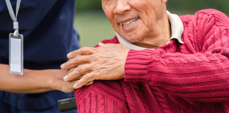 Close-up of elderly mans joyful smile with caregivers hand providing gentle support in the garden
