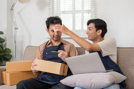 Business partners playfully discussing ecommerce logistics while unboxing in their home officeの写真素材