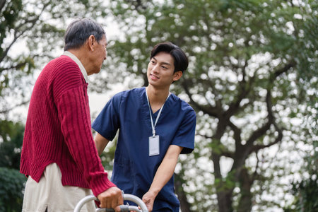 Elderly man and healthcare worker sharing an encouraging moment outdoors while using a walkerの写真素材