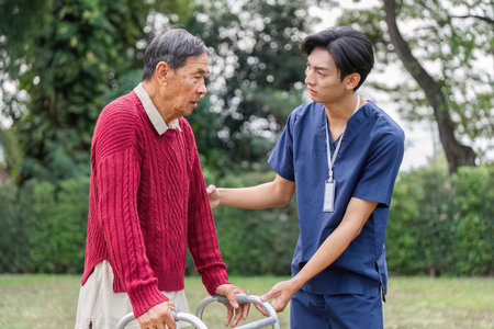 Elderly man receiving compassionate guidance from healthcare professional with a walker outdoorsの写真素材