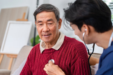 Nurse using stethoscope to check elderly mans heart during a home health check-upの写真素材