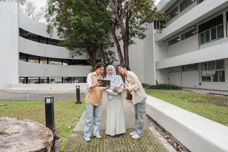 Diverse multicultural women reviewing study materials together outdoors on campus.の写真素材