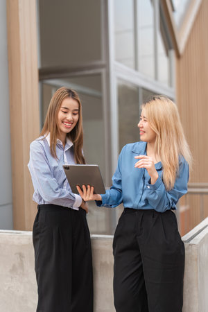 Diverse women sharing information on a tablet, showcasing teamwork and collaboration.