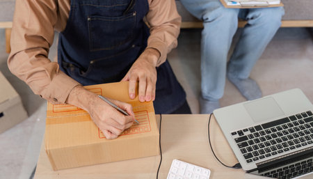 Creative social media marketer preparing product packages during a live stream in their home office