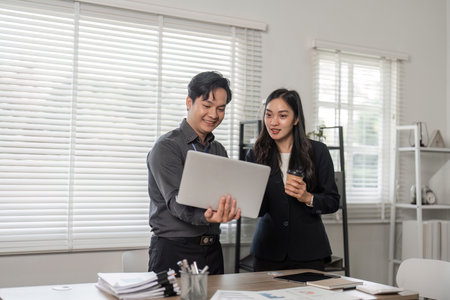 Business partners reviewing progress on a project in a modern office, showcasing teamwork and collaboration.の写真素材