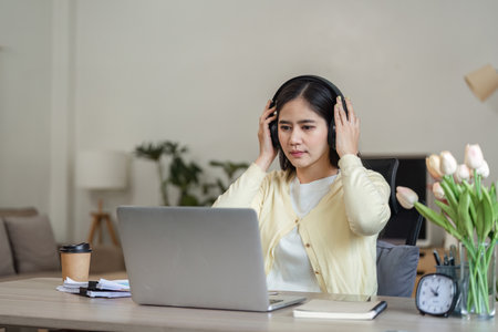 Freelance businesswoman working from home, wearing headphones and focused on her laptop.の写真素材