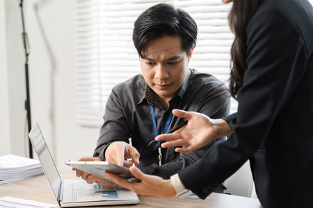 Female professional explaining complex data to a male colleague in a collaborative workspace.の写真素材