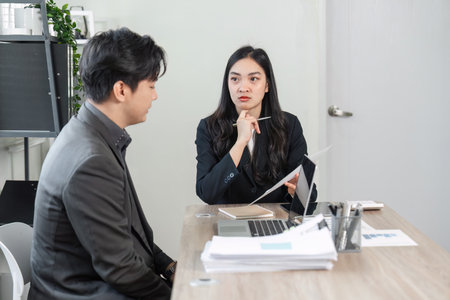 Focused business professionals discussing project details in a modern office setting.の写真素材